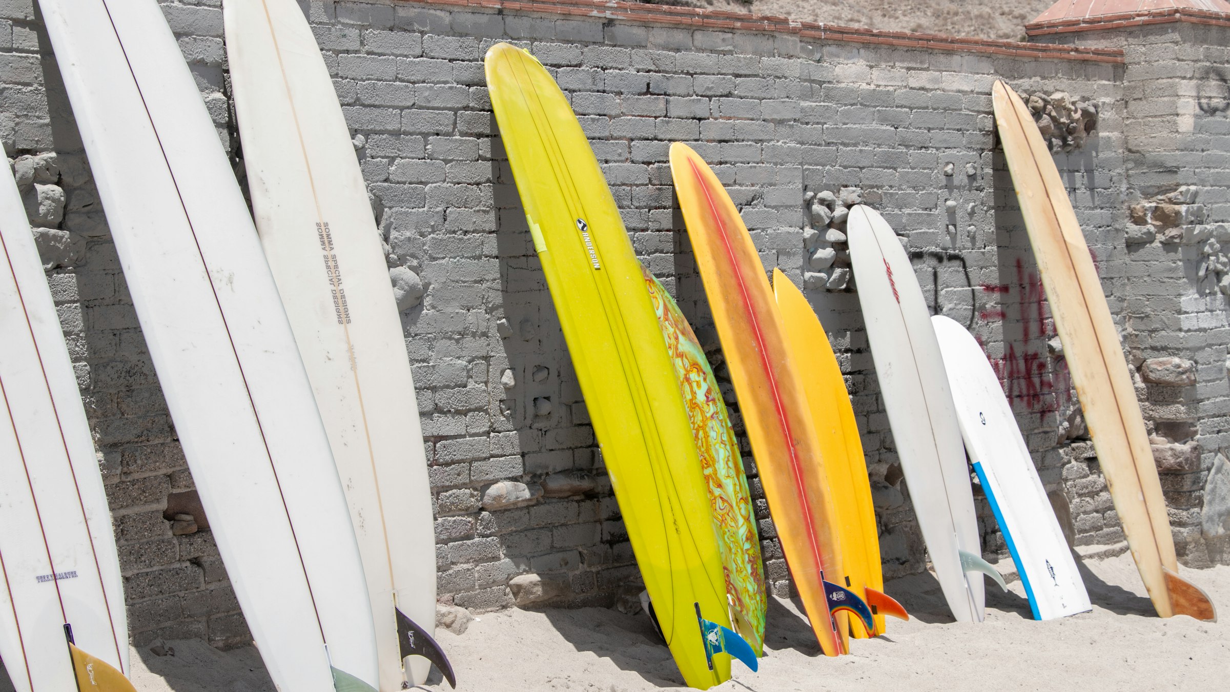 Boards leaned up on the wall by the sand